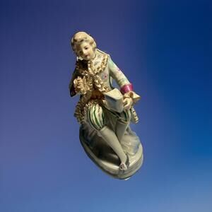 Porcelain Figurine Of A Gentleman In 18th Century Attire Seated With A Book.